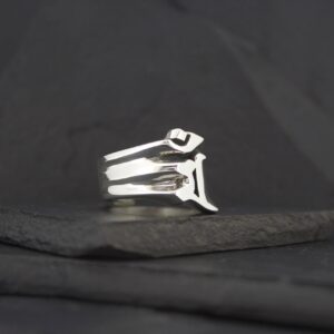 Silver ring with a unique geometric design on a black surface.