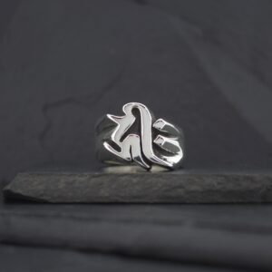 Silver ring with a gothic-style letter design on a dark surface.