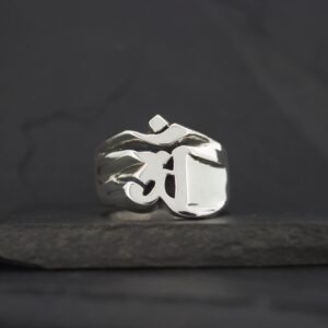 Silver ring with a raised Om symbol on a dark background.