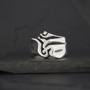 A silver ring with an abstract, artistic design on a dark background.
