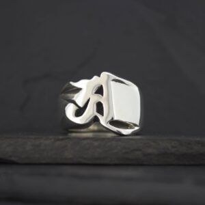A silver ring with a bold, rectangular face on a dark background.