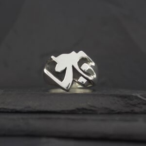 A silver ring with a unique geometric design on a dark surface.