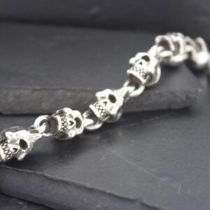 Silver skull chain bracelet on a dark surface.