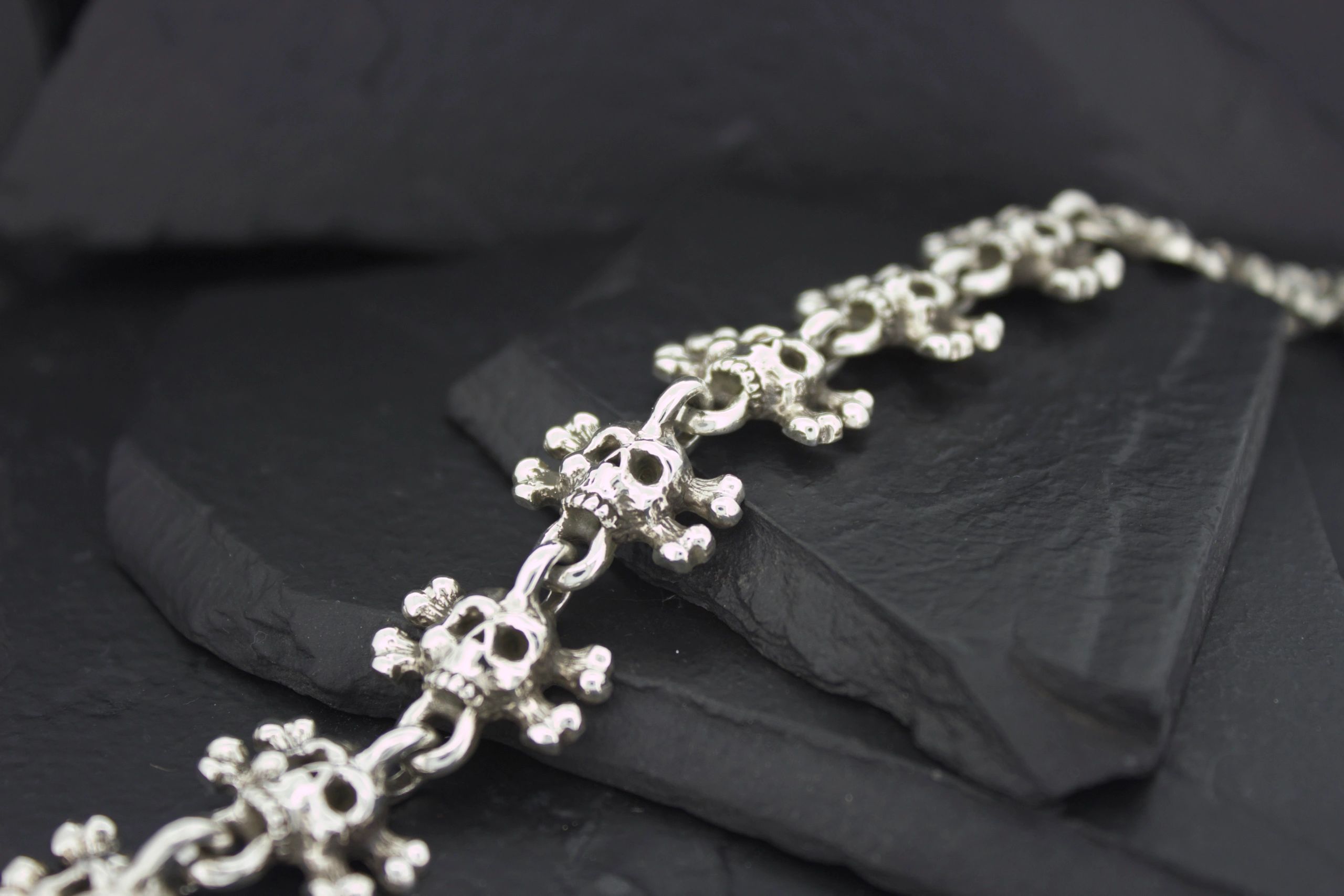 Close-up of a detailed silver bracelet on dark stone.