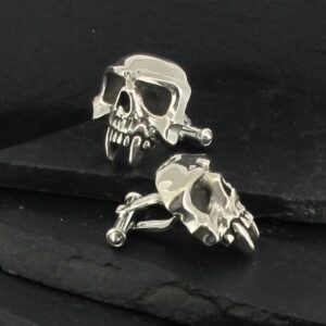 Silver skull-shaped earrings with a dark background.