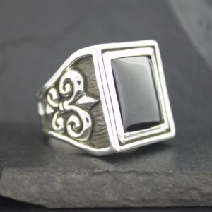 Elegant silver ring with black rectangular stone and intricate side design.