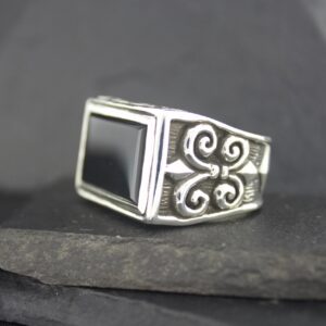 Elegant silver ring with a black square stone and intricate swirl designs.