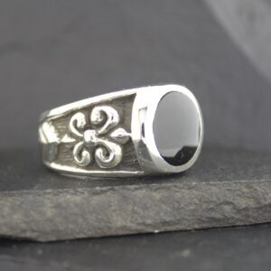 Silver ring with black stone and fleur-de-lis design.