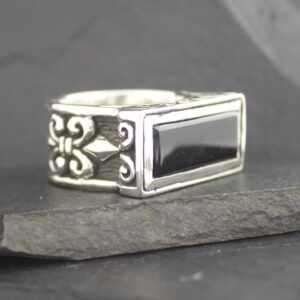 Silver ring with a black rectangular stone and intricate side designs.