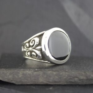 Silver ring with a black oval stone and intricate swirl designs.