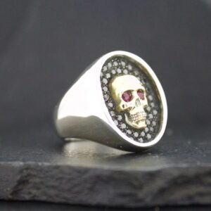 Silver ring with a skull design and red eyes.