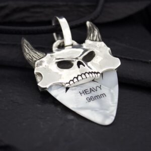 A silver pendant shaped like a devil's face with horns and engraved text.